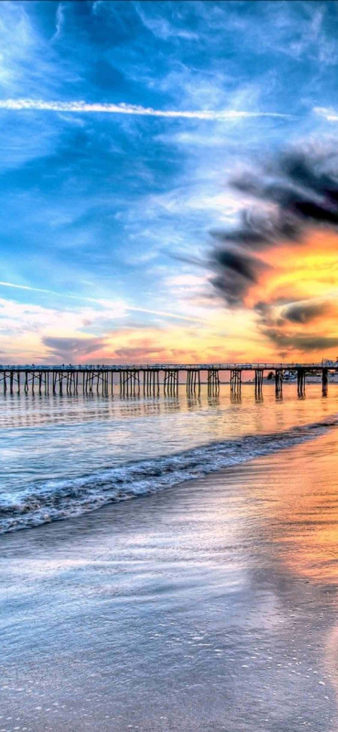 a pier with a sunset over the ocean Wallpapers