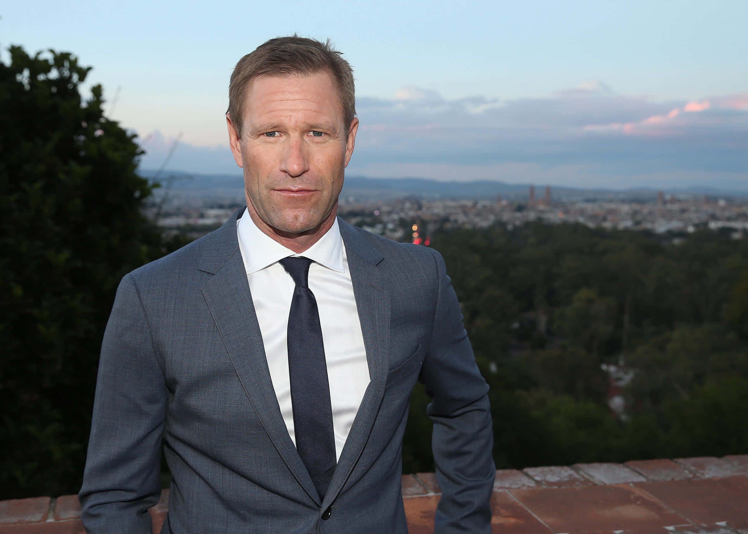 Aaron Eckhart med blå himmel og by Wallpapers