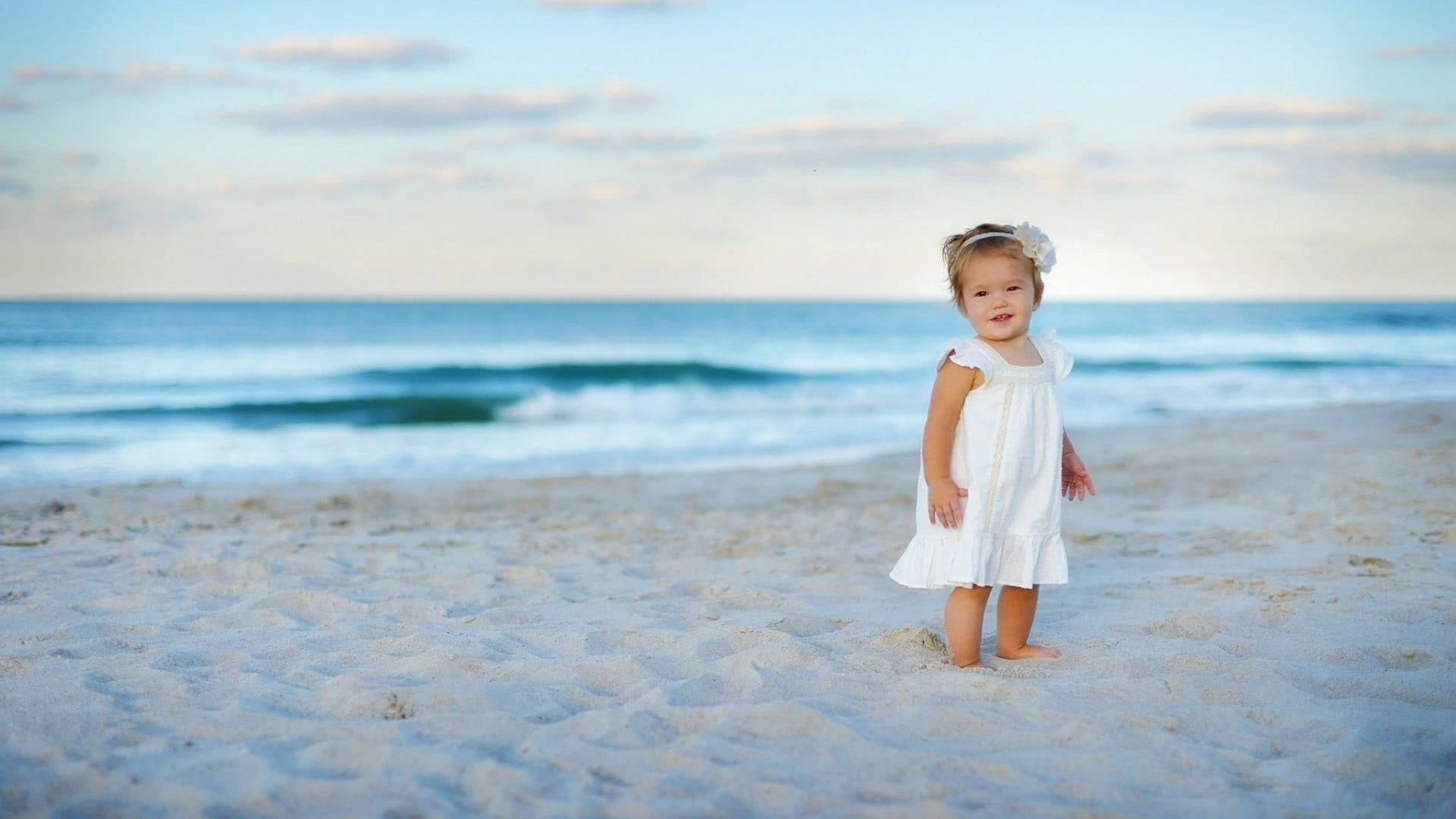 Babypige i hvid kjole på stranden Wallpapers