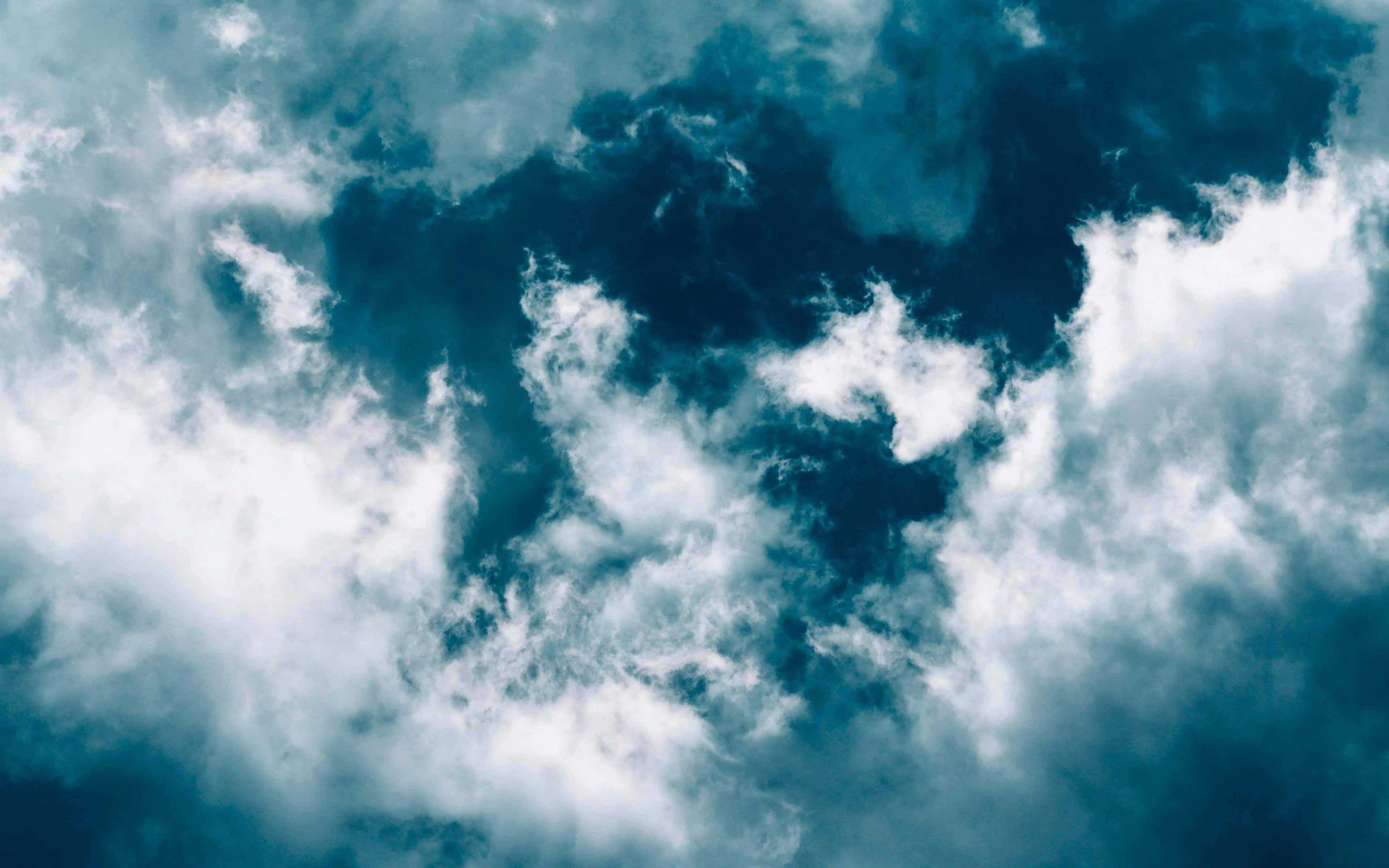 en blå himmel med skyer og et fly, der flyver over den Wallpapers