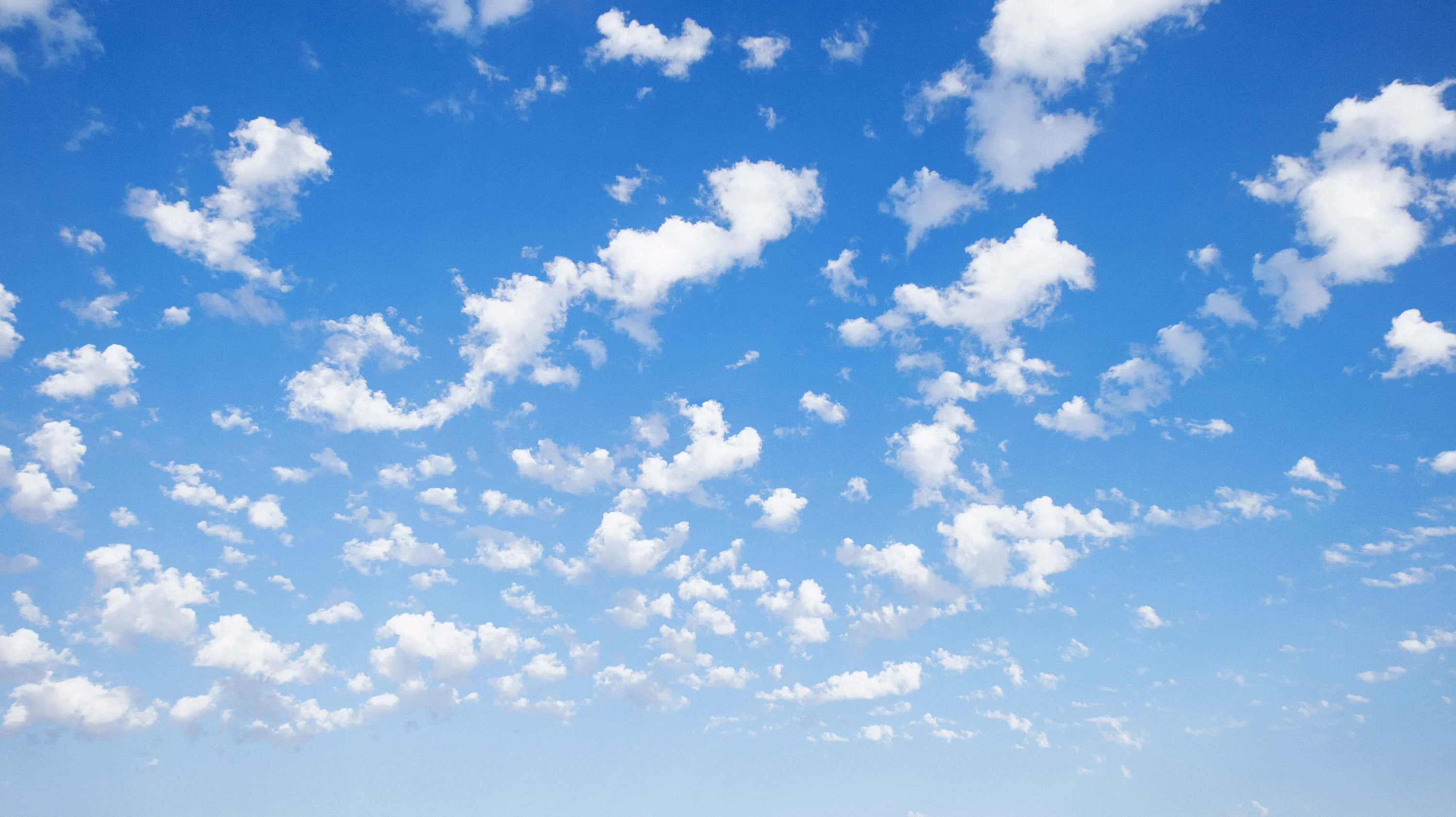 En blå himmel med hvide skyer og en græsklædt mark Wallpapers