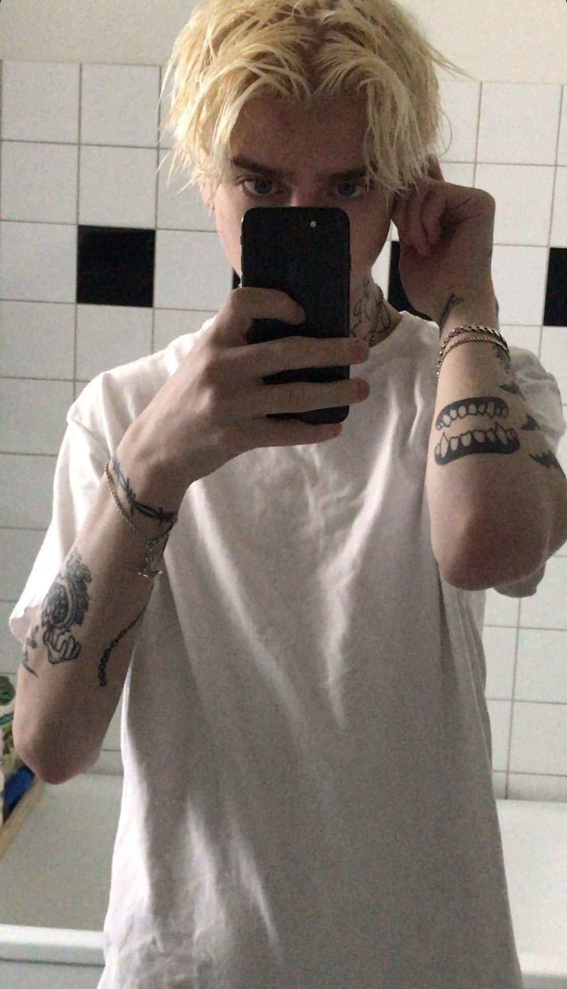 En dreng stående i profil iført et urbant outfit og et par hvide sneakers Wallpapers