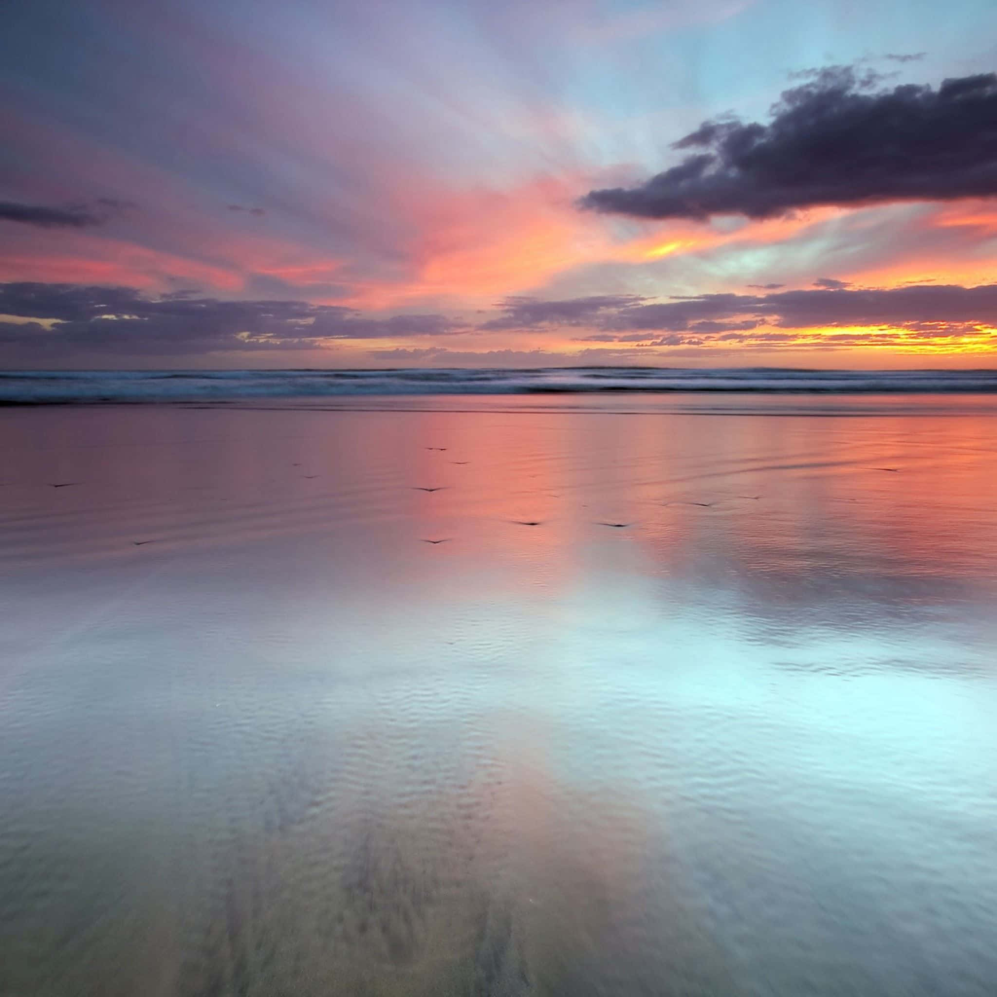 en farverig solnedgang ses fra stranden Wallpapers