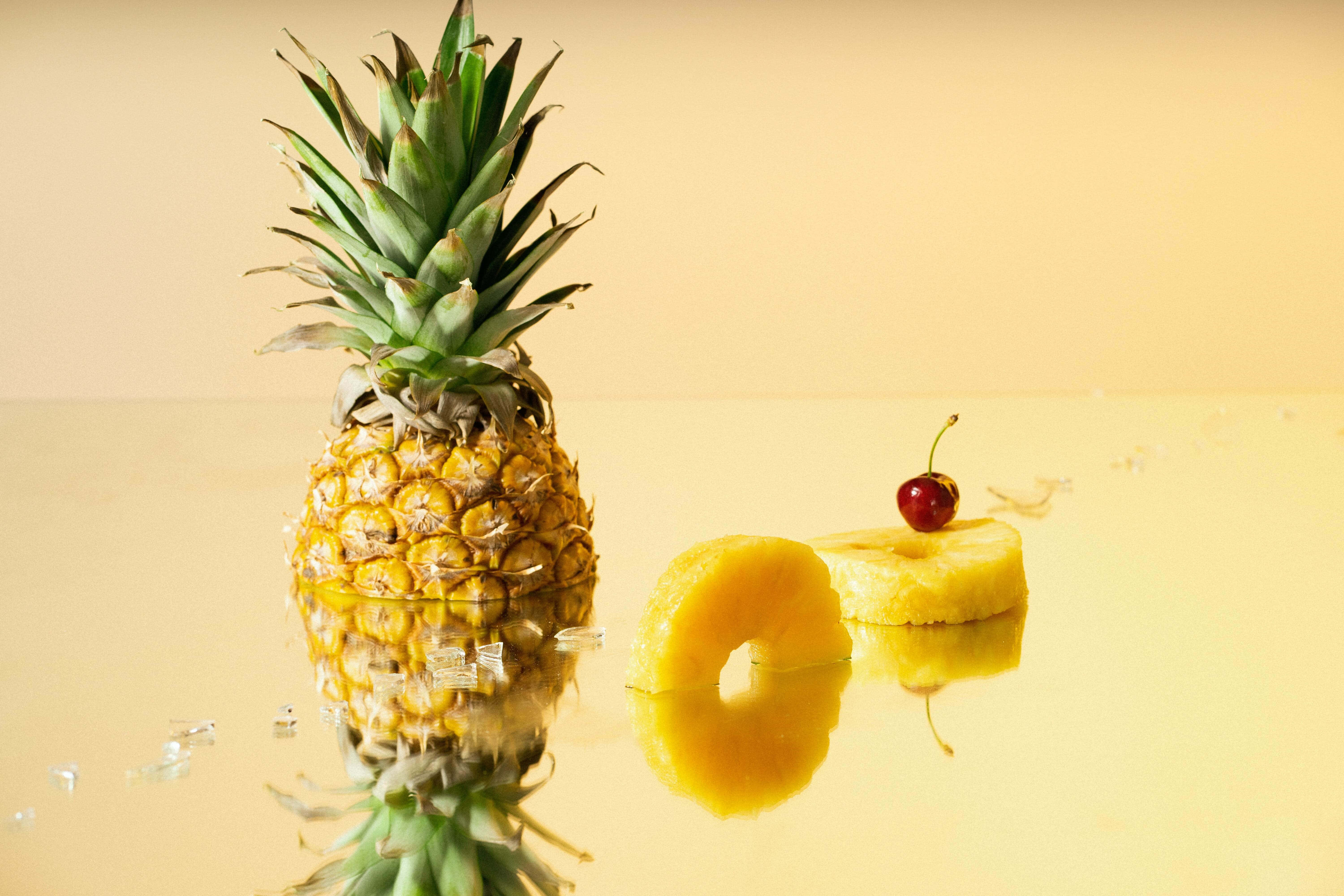 En frisk og saftig ananas står i forgrunden af en malerisk solnedgang. Wallpapers