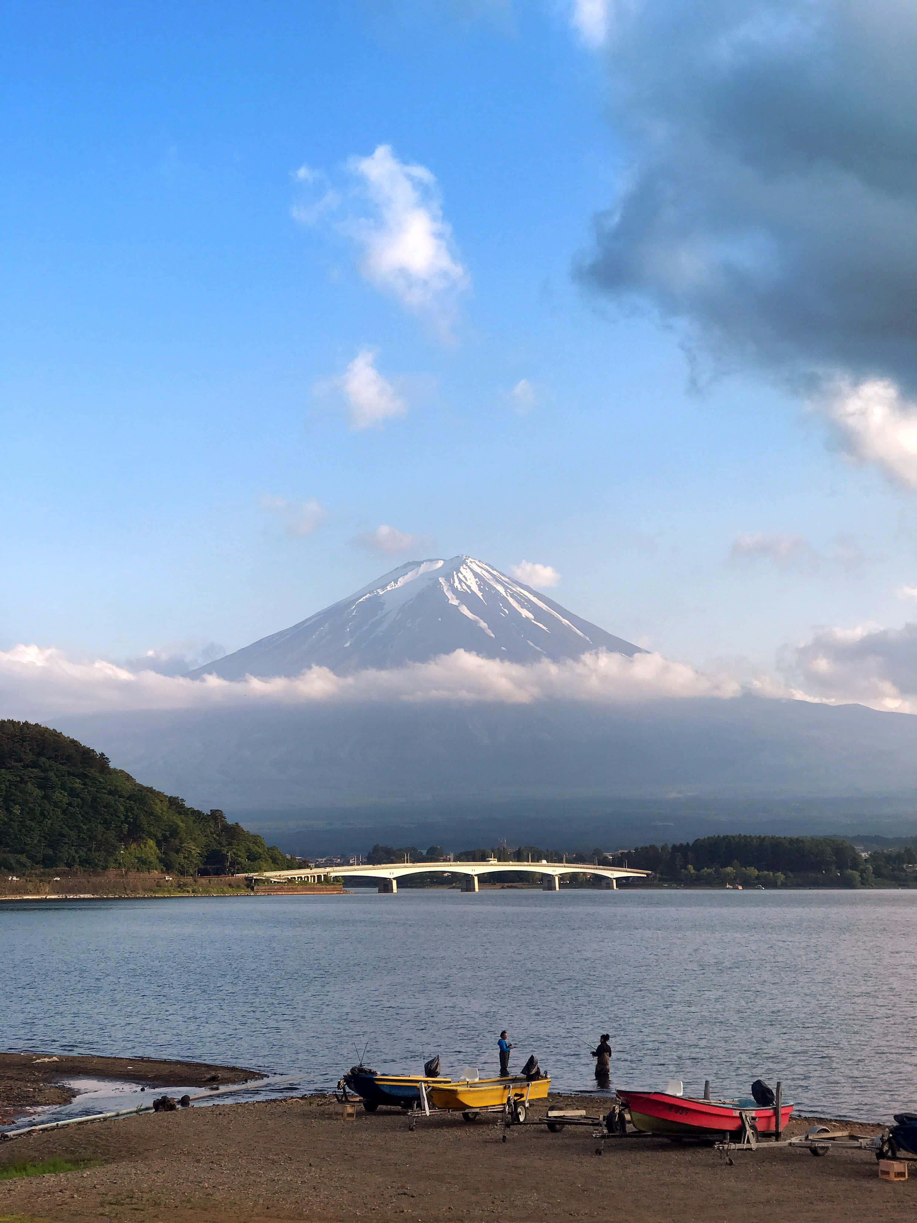 en gruppe mennesker sidder på stranden med et bjerg i baggrunden Wallpapers