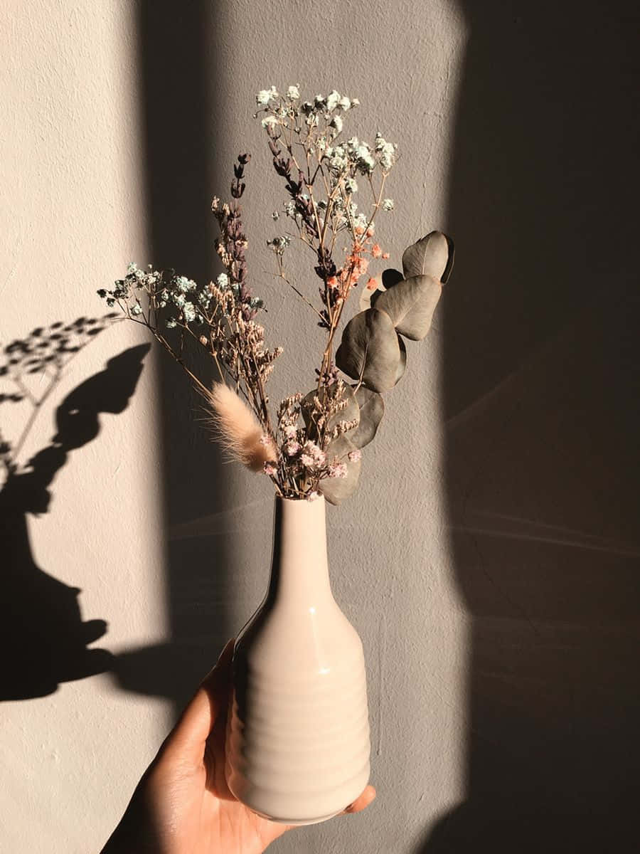 En hvid vase med et par tørrede blomster i Wallpapers