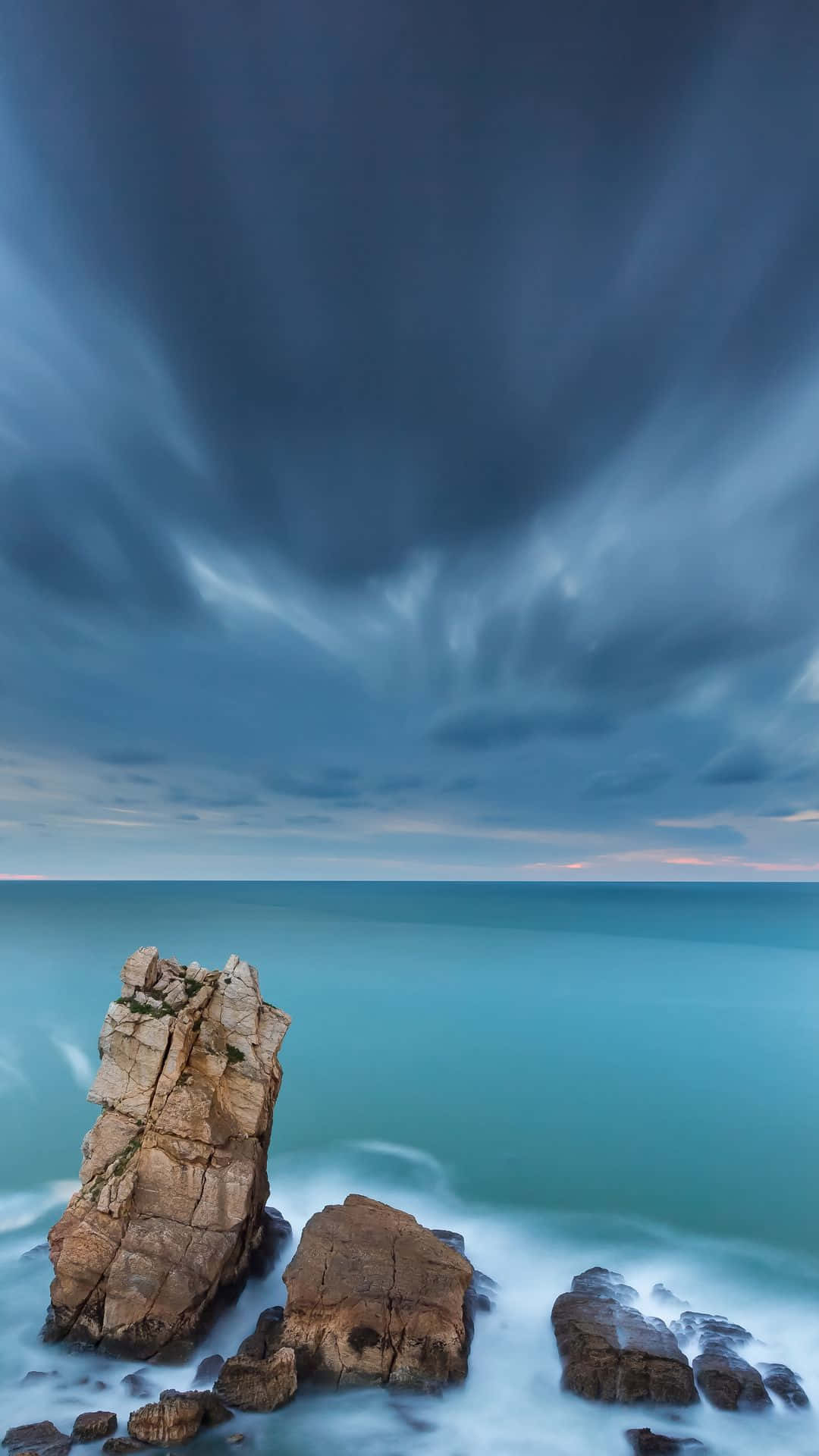 En klippeformation med en mørk himmel og hav Wallpapers