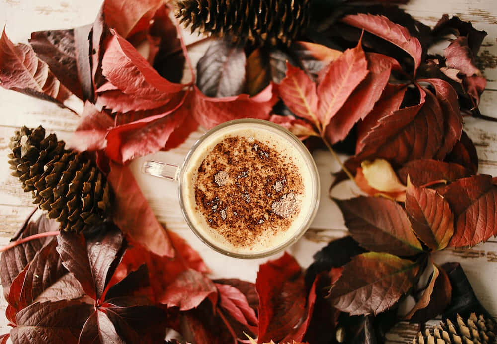 en kop kaffe omgivet af blade og kogler Wallpapers