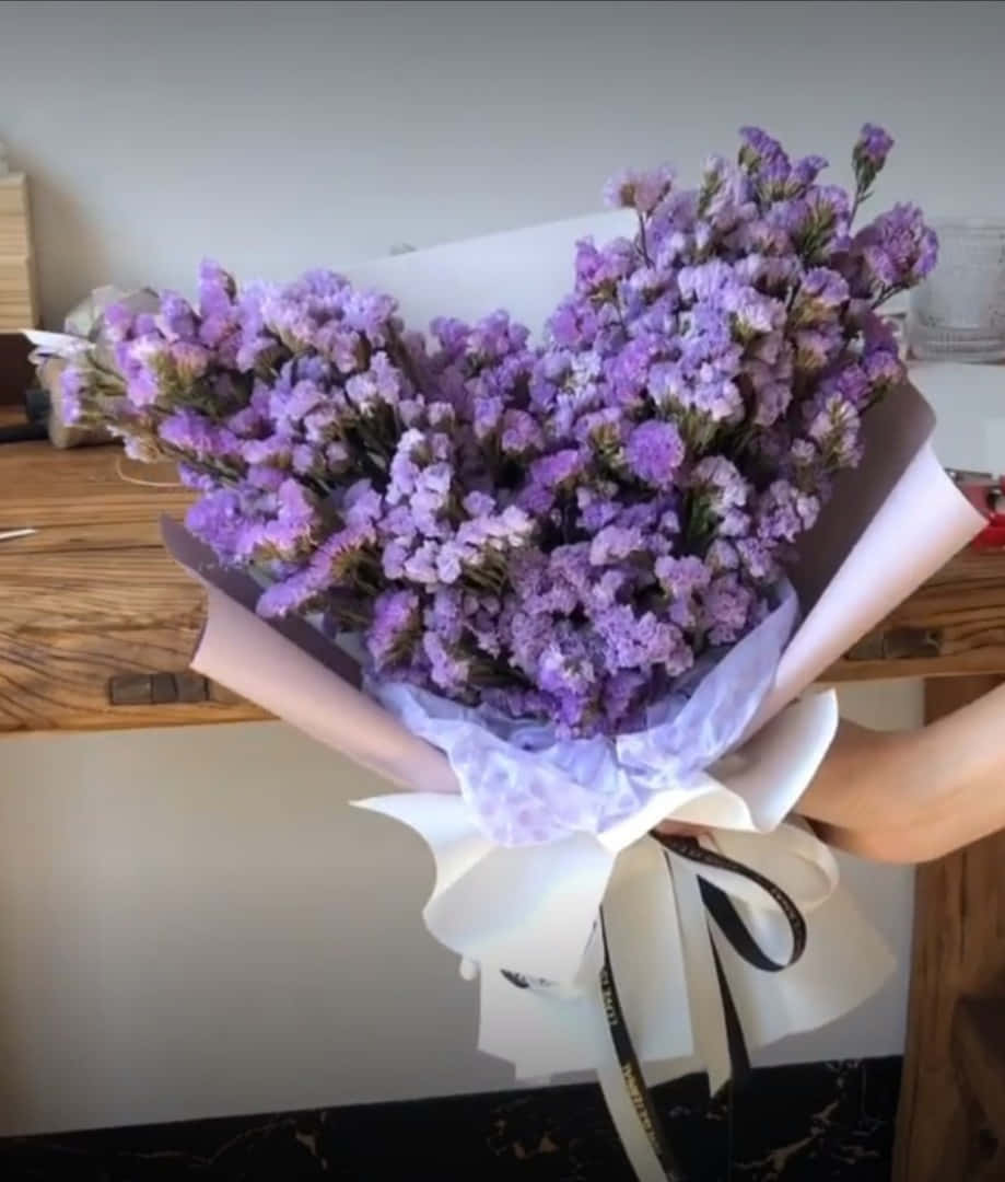en kvinde holder en buket lilla blomster Wallpapers