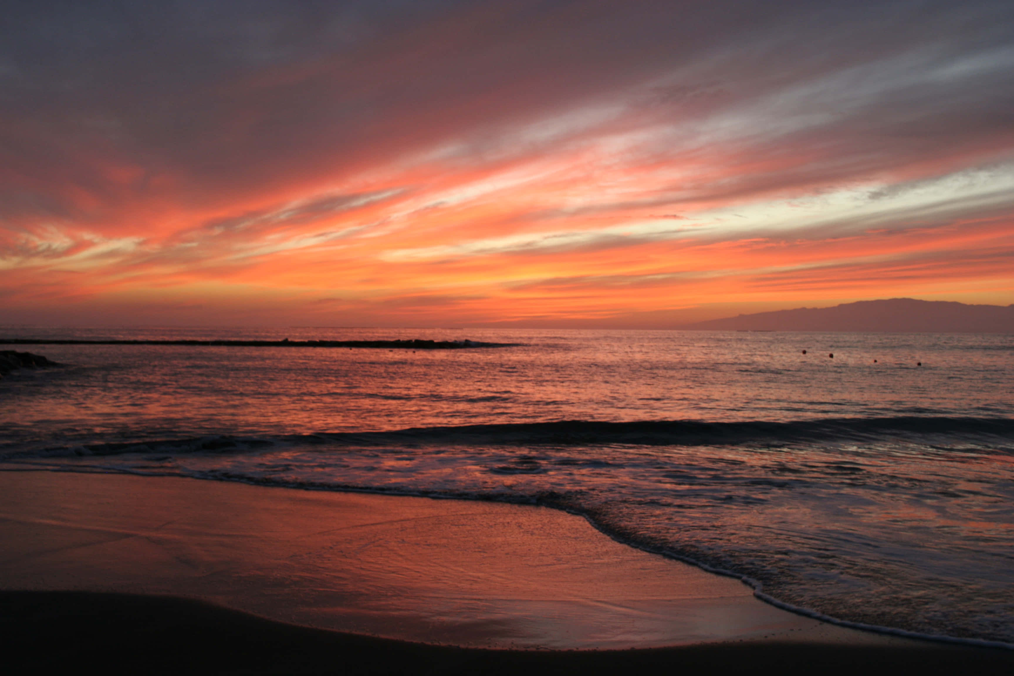 En levende strandsolnedgang med smukke orange, guld og blå nuancer Wallpapers