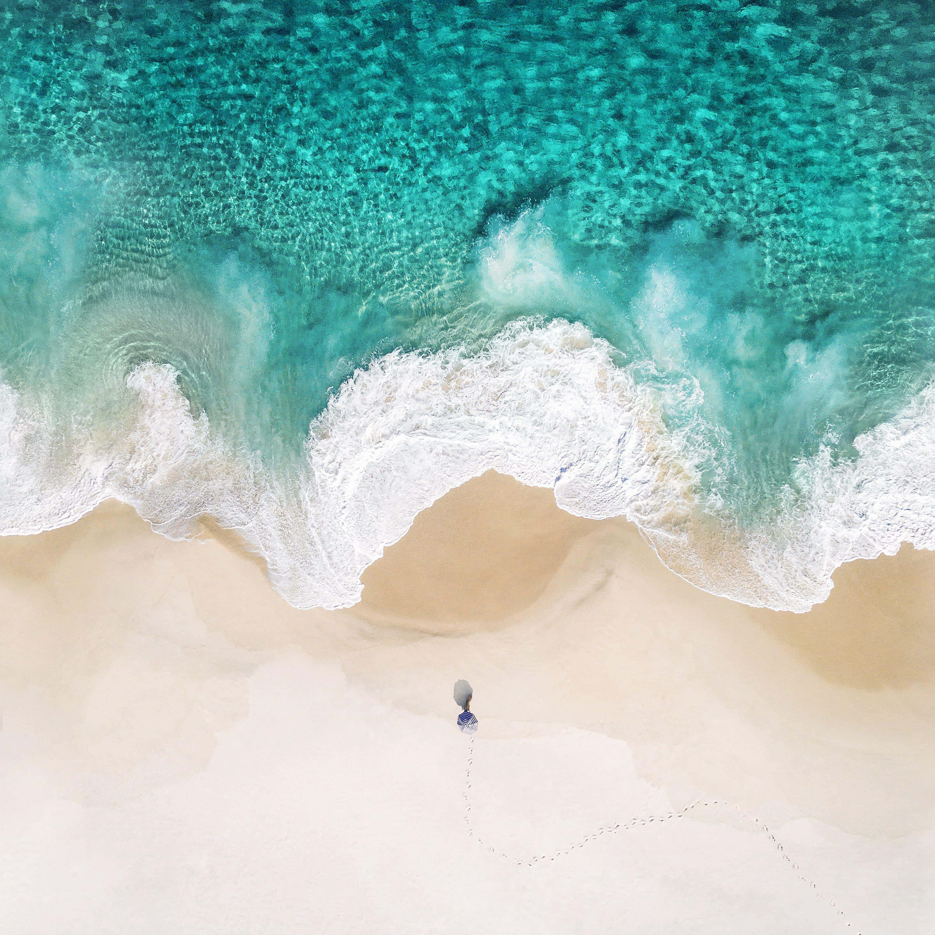 en person går på stranden nær havet Wallpapers