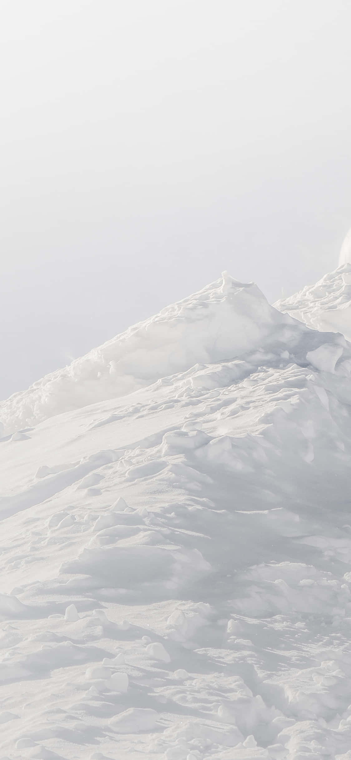 En person står på ski ned ad en snedækket skråning Wallpapers