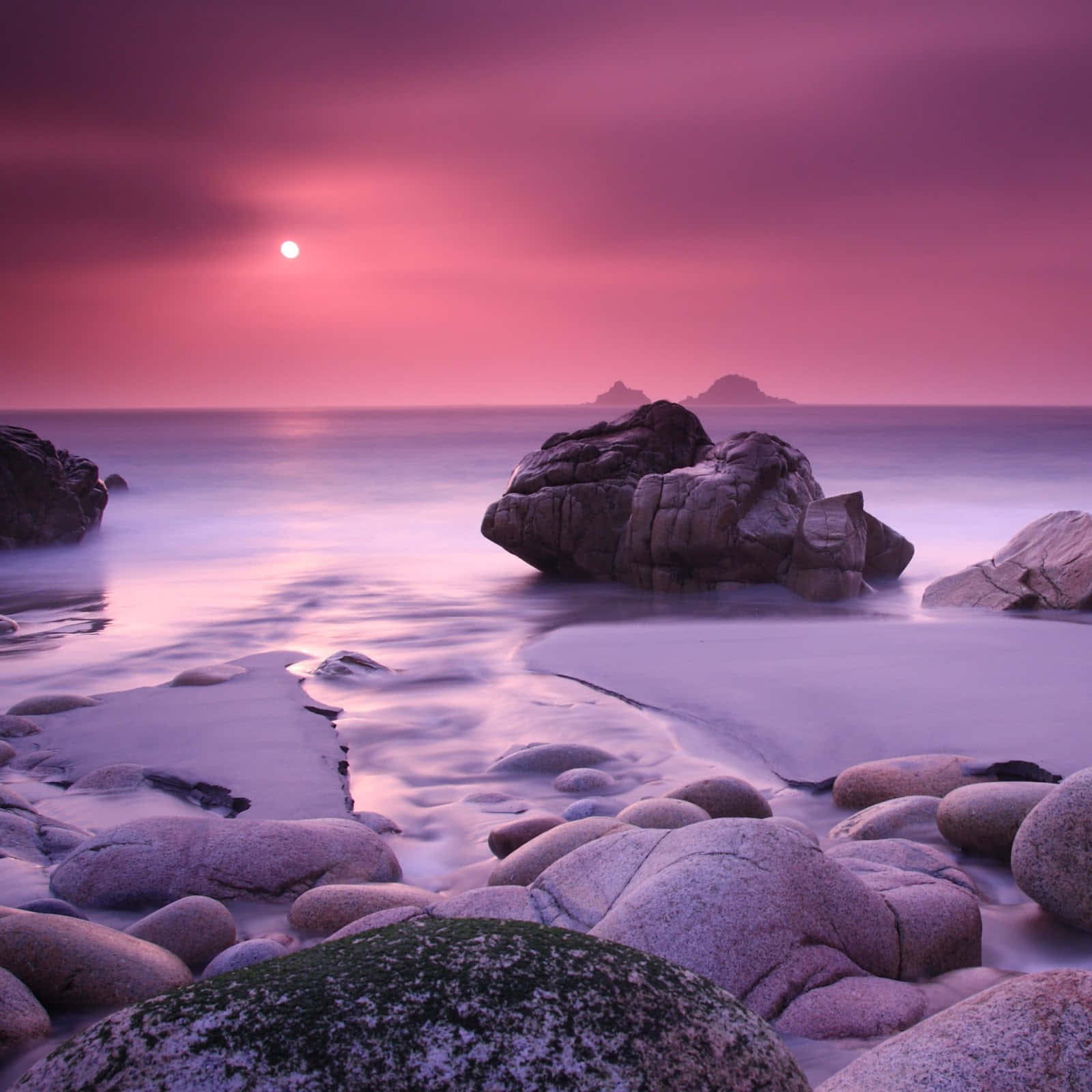 en pink solnedgang over klipper og vand Wallpapers