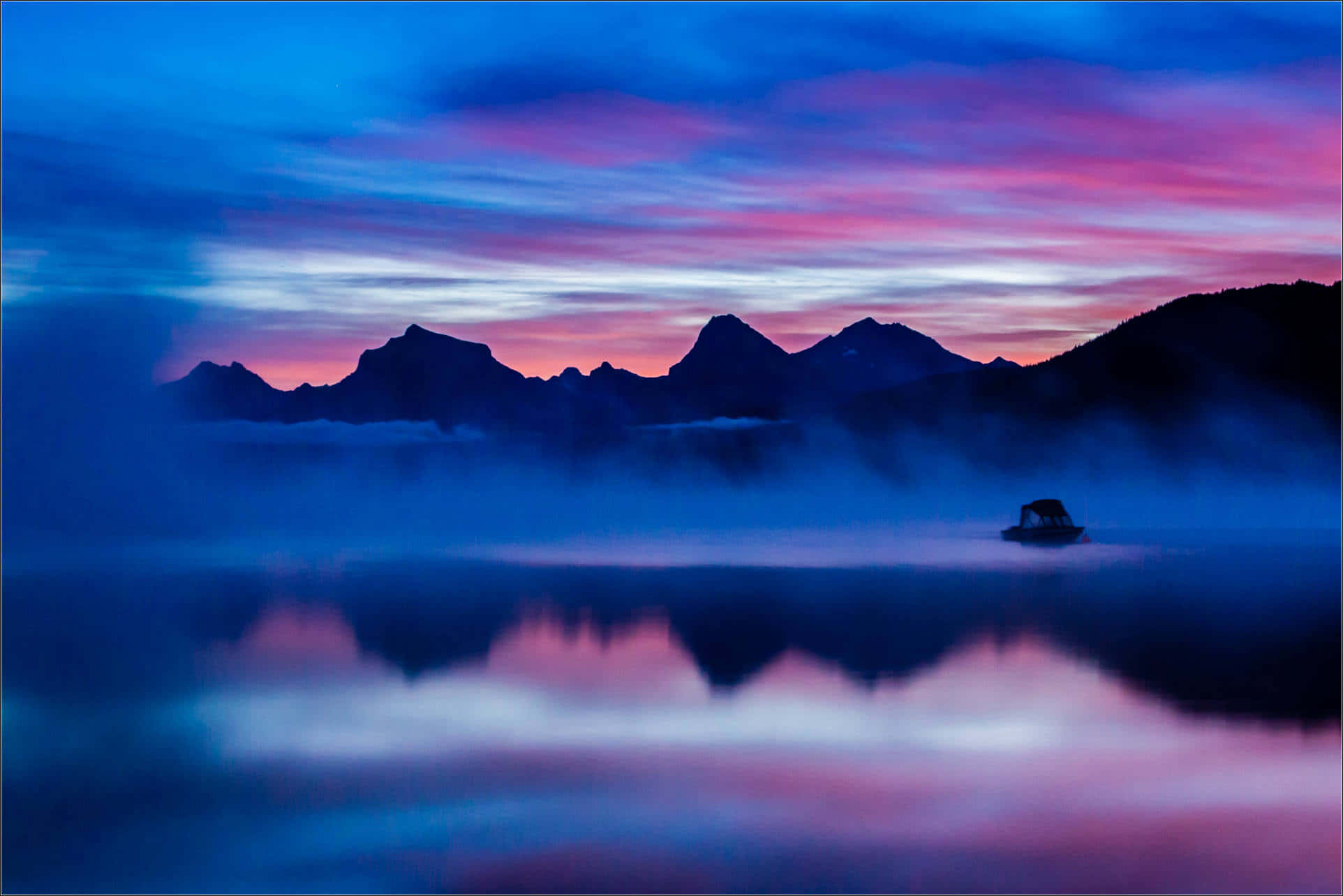 en sø med bjerge og tåge i baggrunden Wallpapers