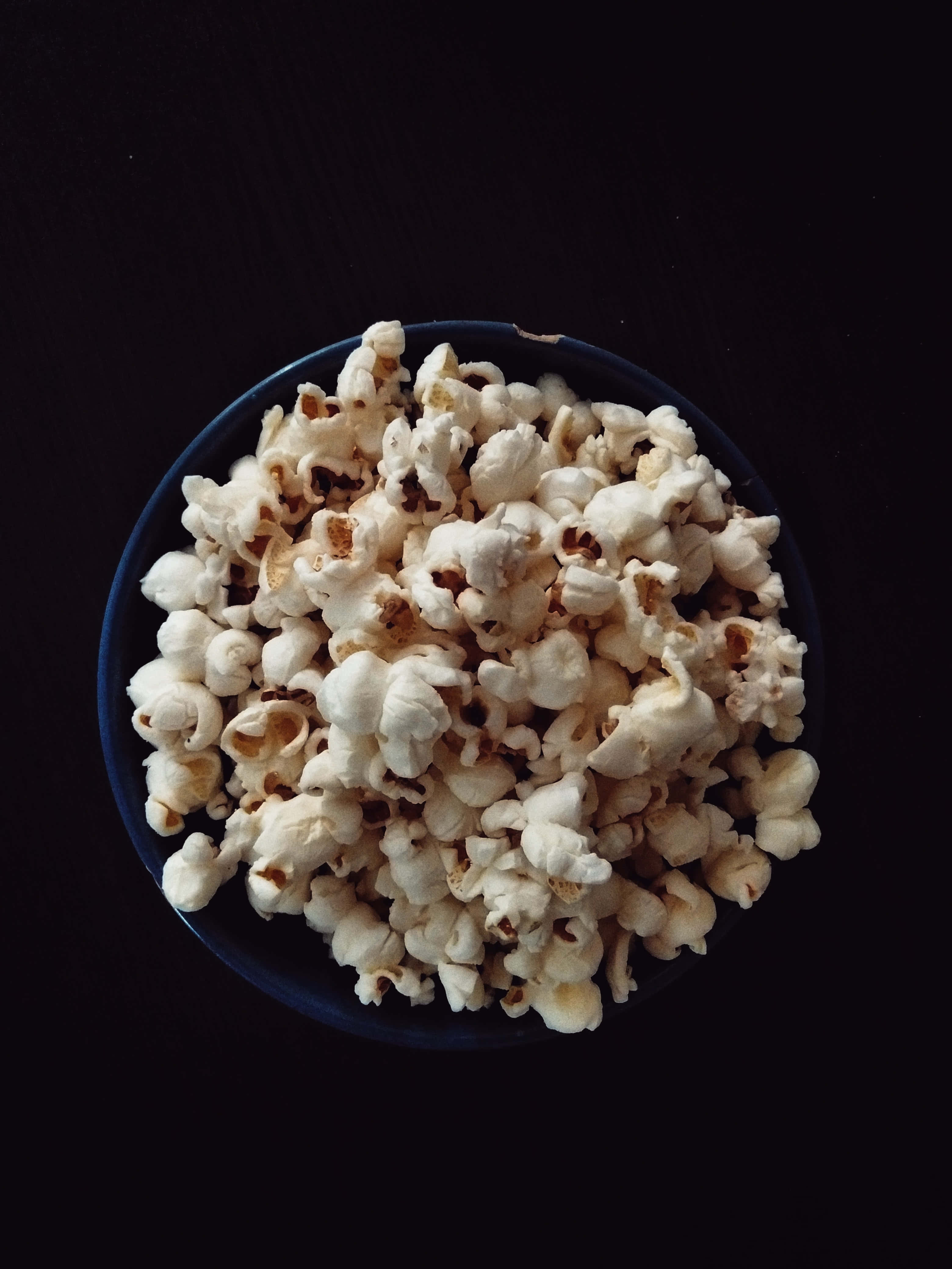 en skål popcorn på et sort bord Wallpapers