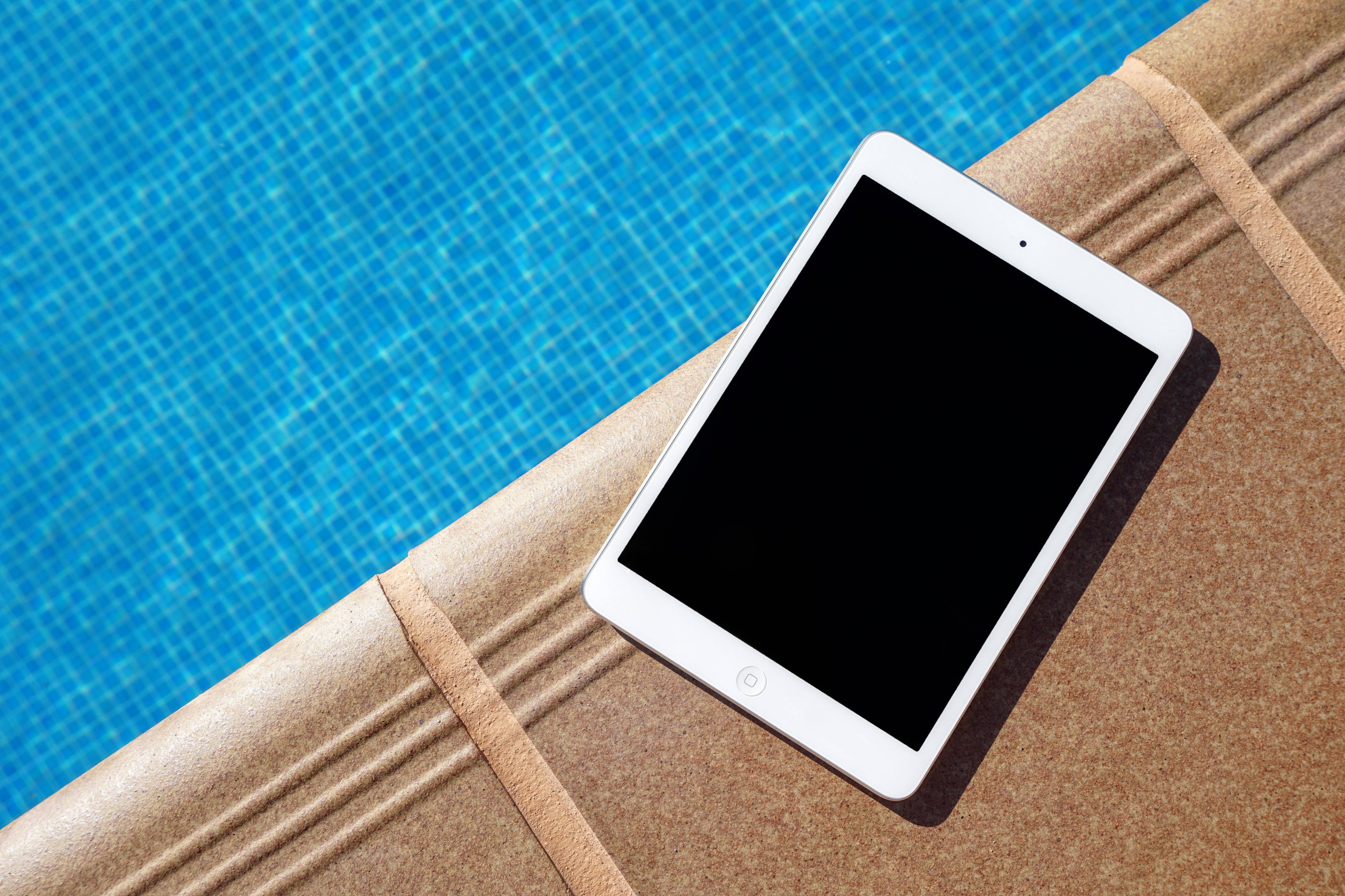 En slank sølv iPad vist på et minimalistisk gråt skrivebord Wallpapers