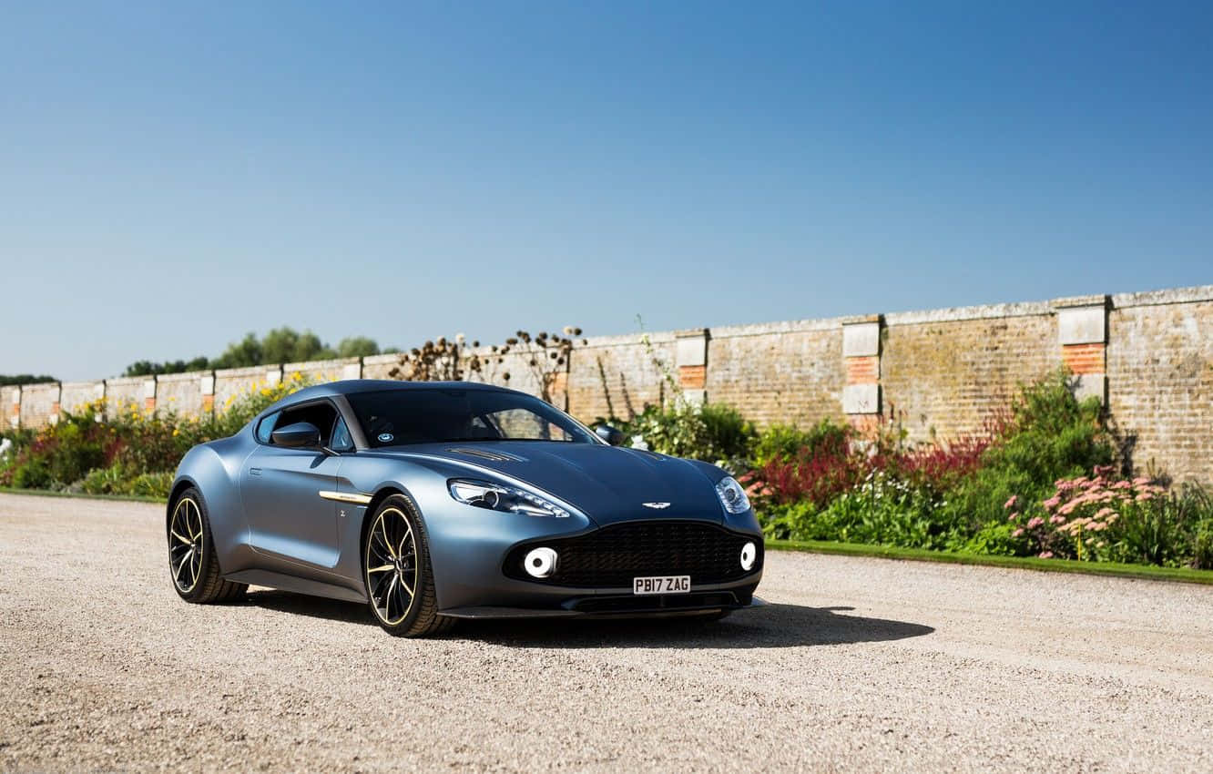 Enestående Aston Martin Vanquish i bevægelse på en naturskøn vej Wallpapers