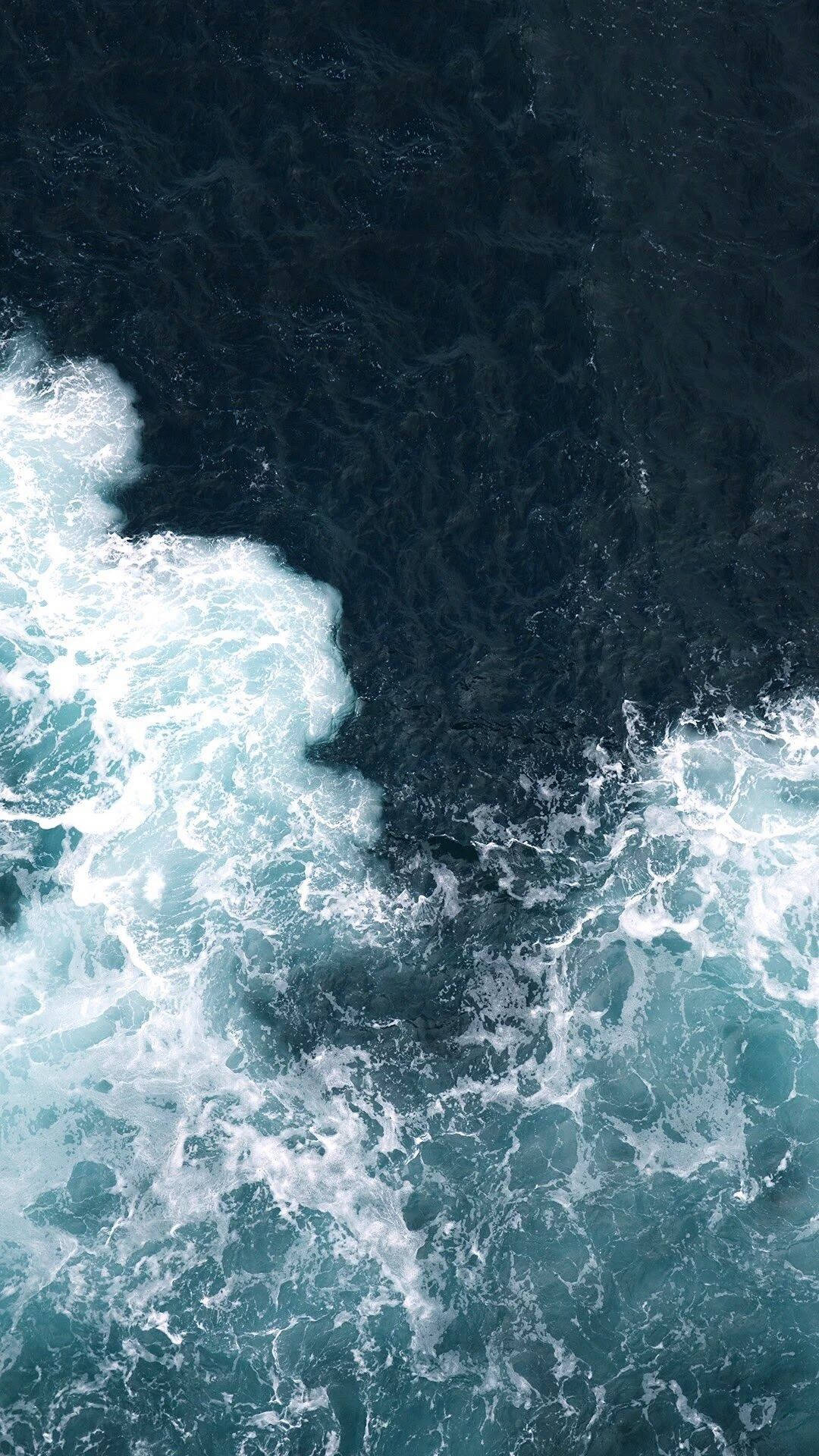 Et luftfoto af havets kraft, når bølgerne bryder mod kysten. Wallpapers