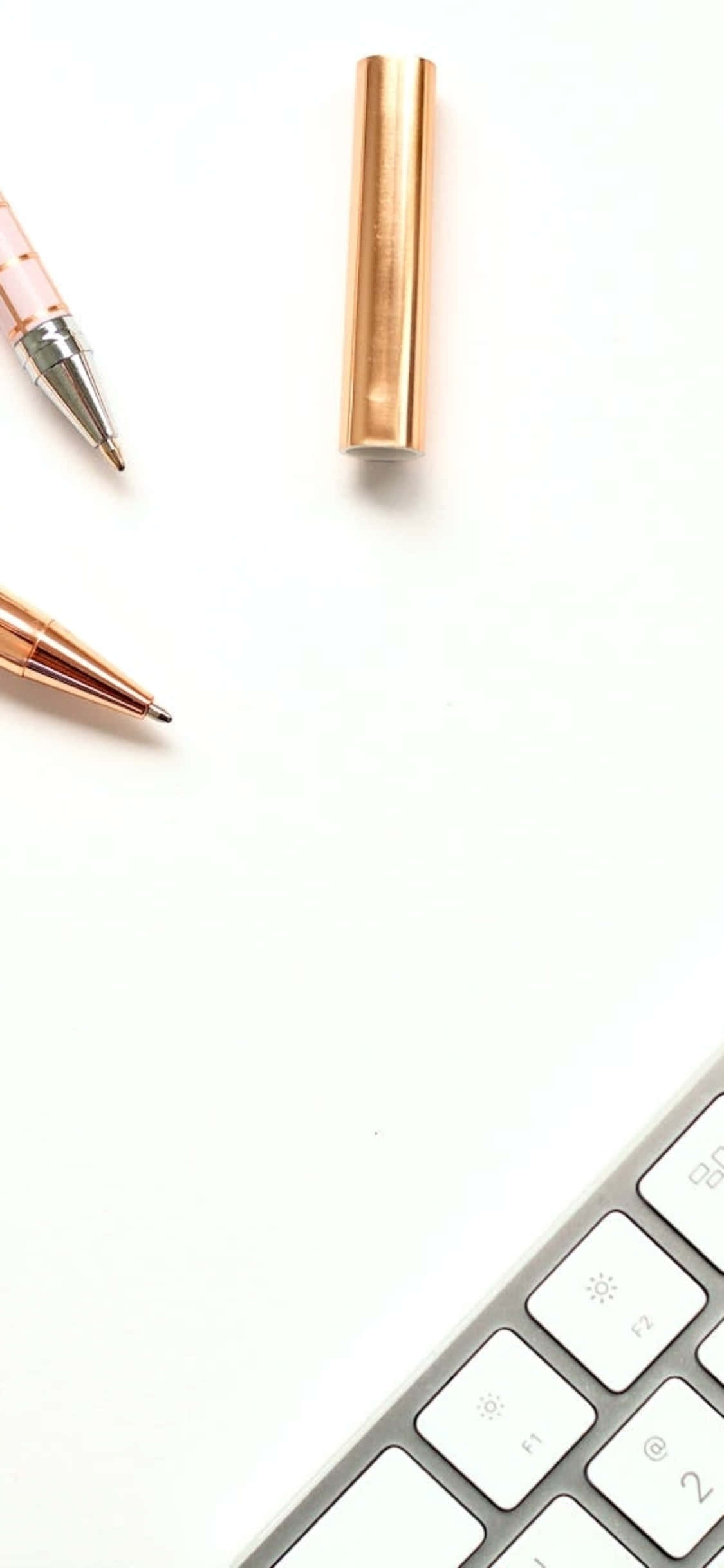 iPhone X Skrivebordsbaggrund Gyldne penne ved siden af tastatur Wallpapers