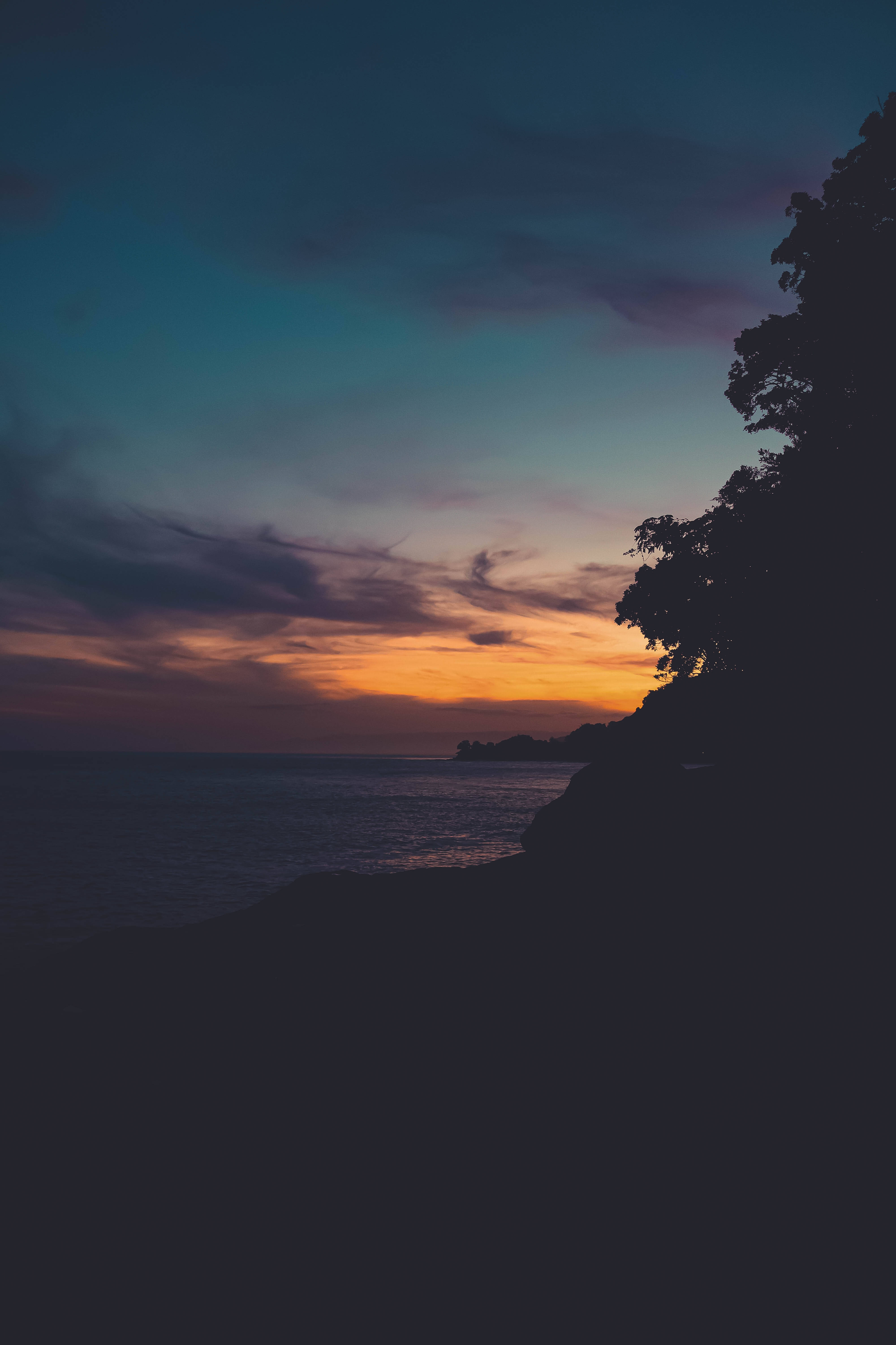 Klare røde og orange toner lyser op over et fredeligt landskab under solnedgang Wallpapers