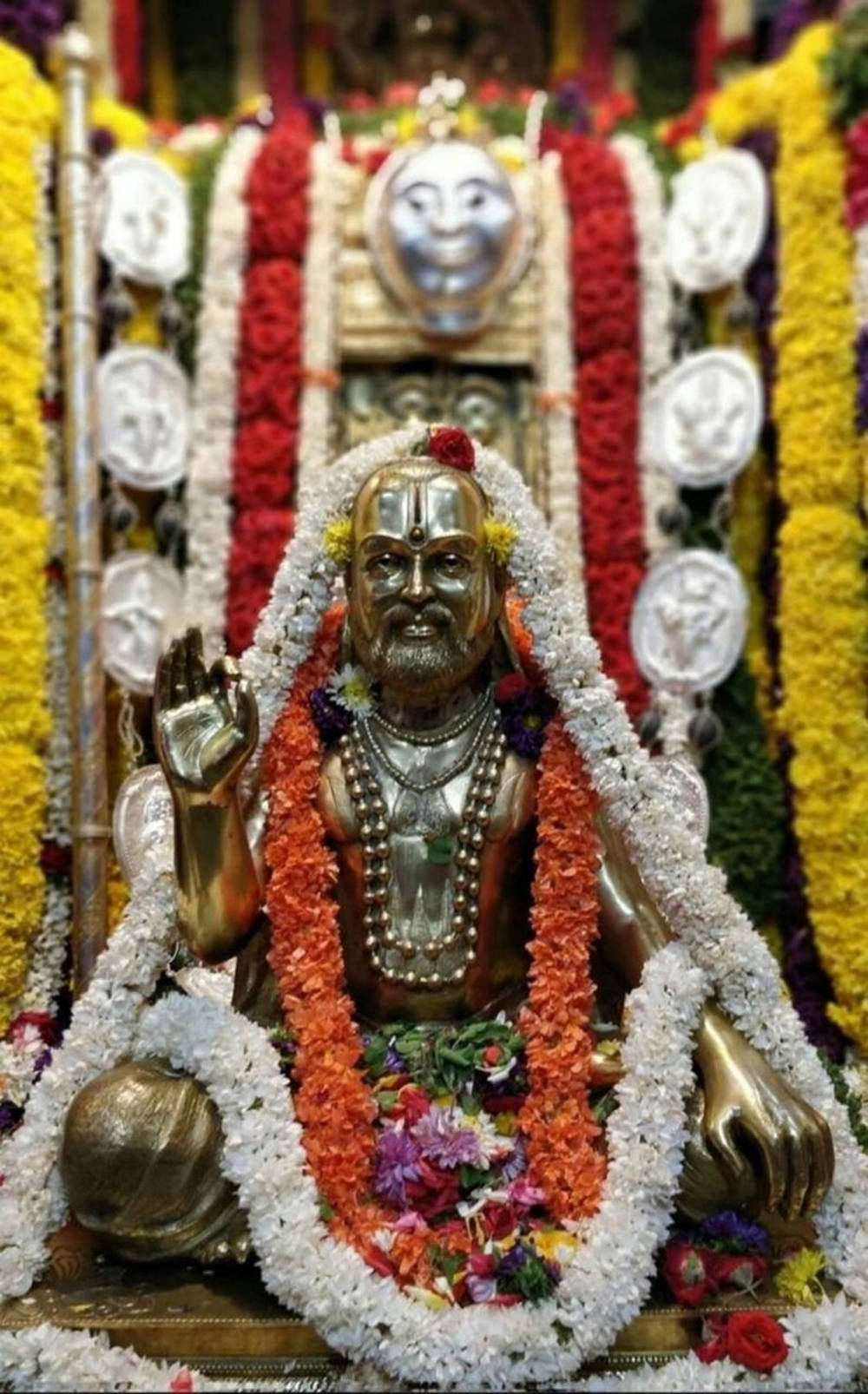 Majestætisk gylden statue af Raghavendra prydet med blomsterkranse Wallpapers