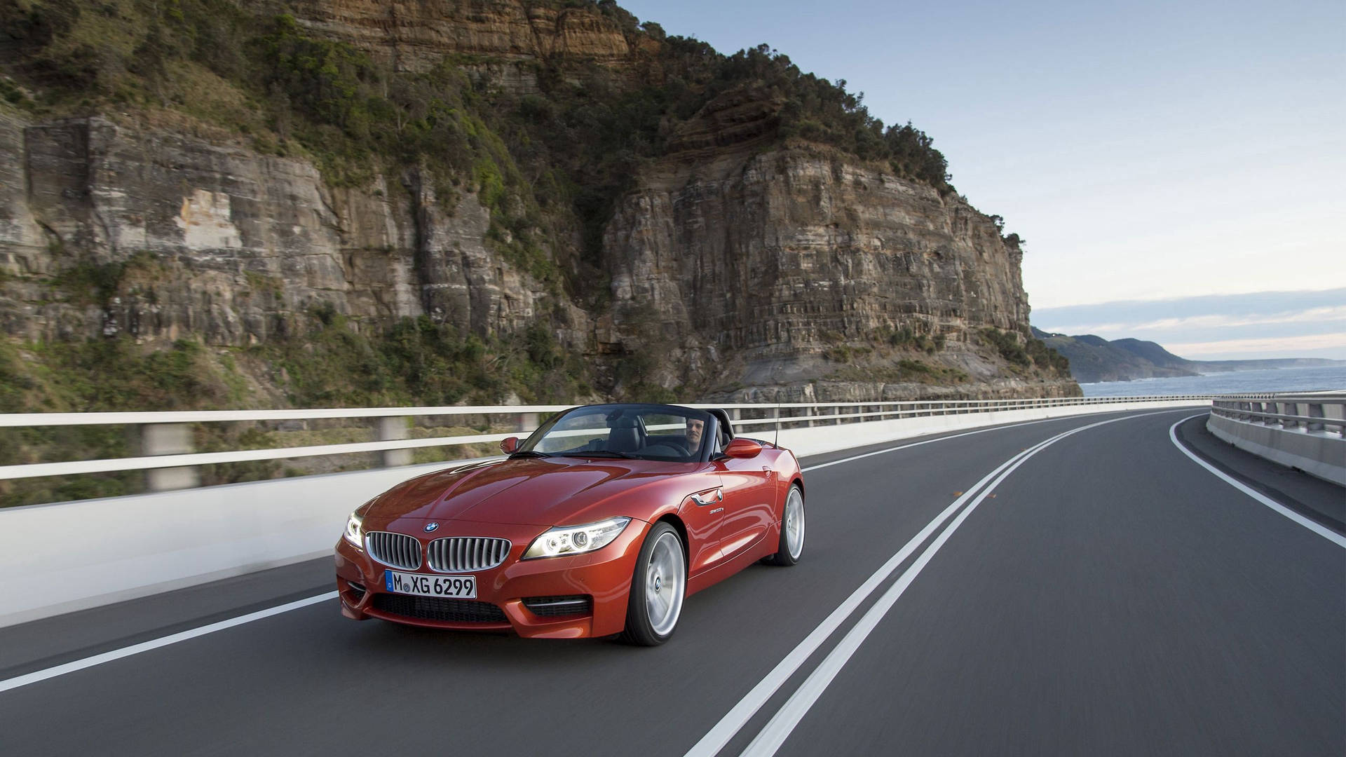 Orange BMW Z4 bil på vej ved siden af bjerg baggrundsbillede — Bmw Wallpapers