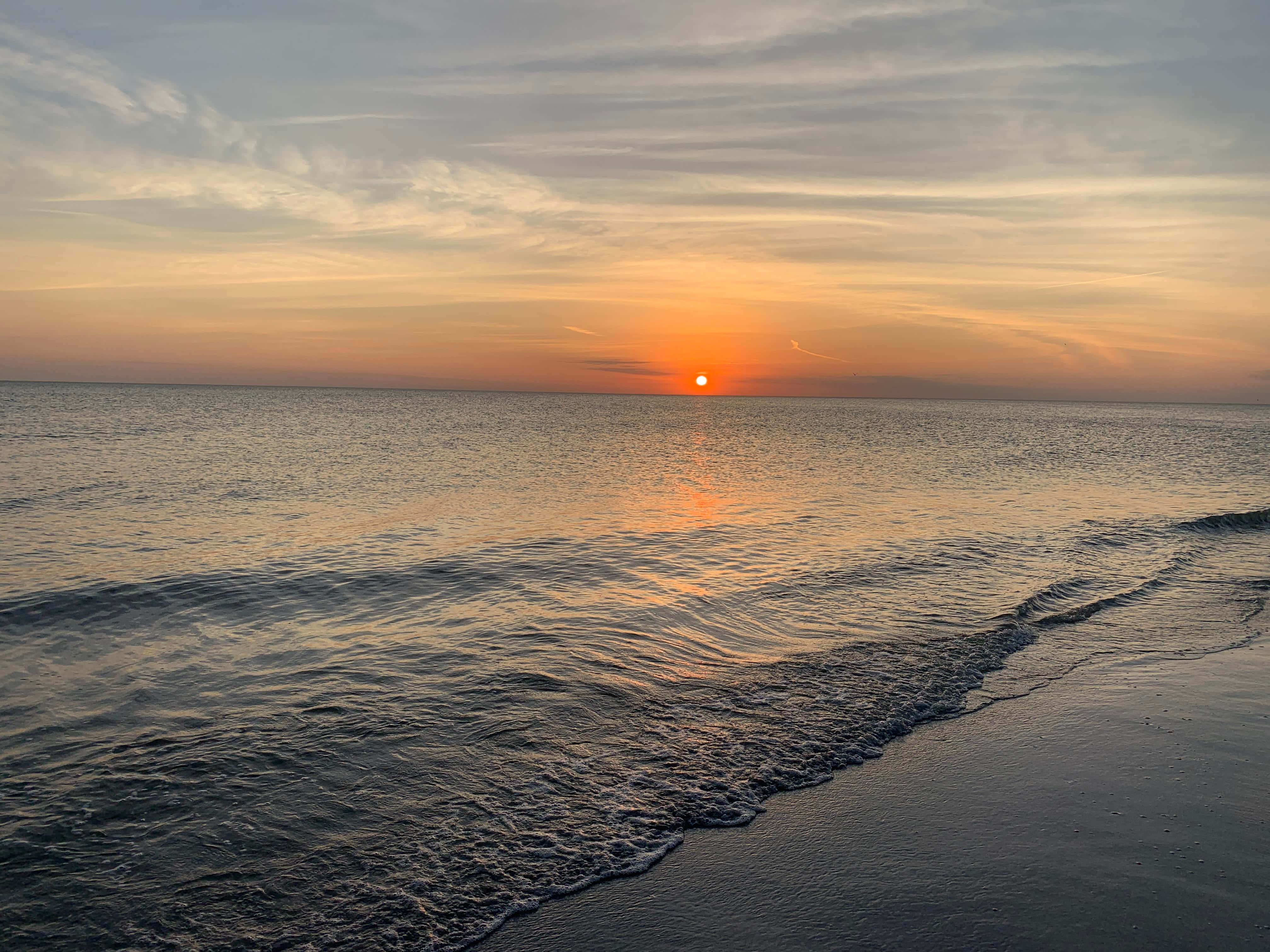 Nyd de strålende farver ved en strandsolnedgang Wallpapers