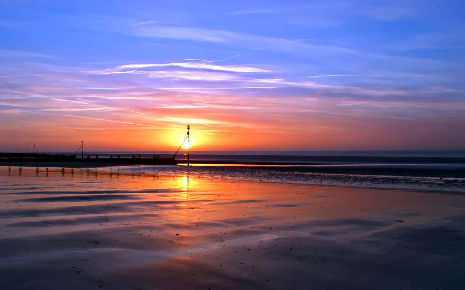 Nyd den gyldne skønhed ved en rolig strandsolnedgang Wallpapers