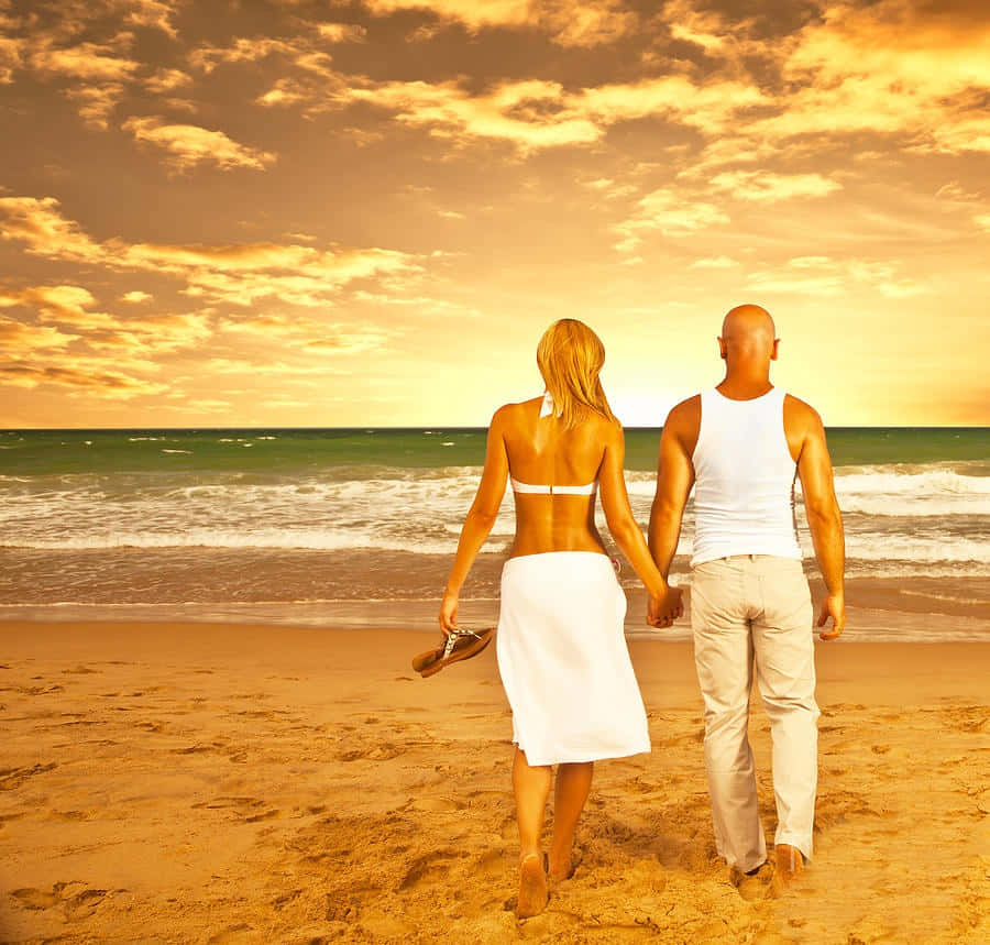 Par på stranden under orange himmel Wallpapers