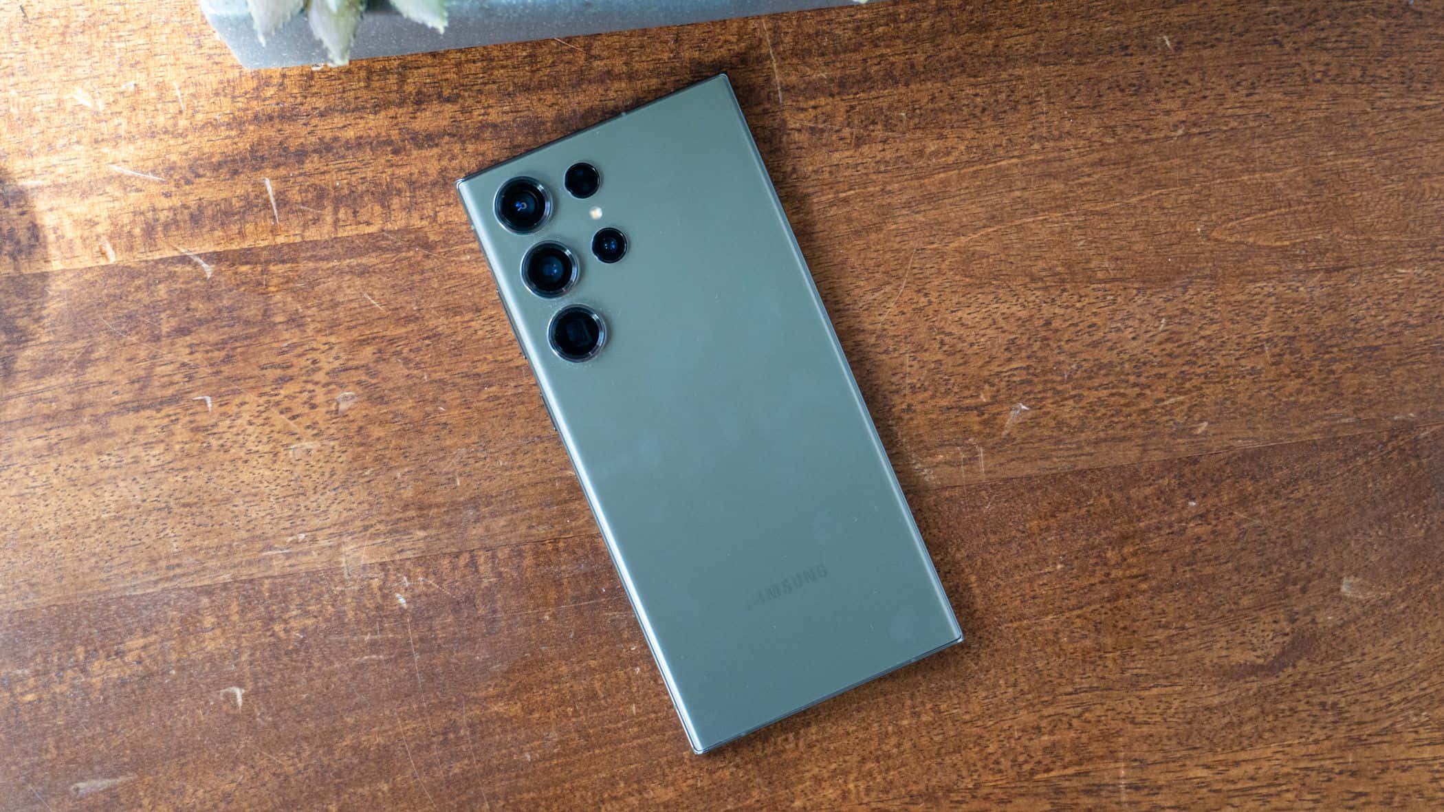 Samsung S23 Ultra grøn bagside med kameraarray på træoverflade Wallpapers