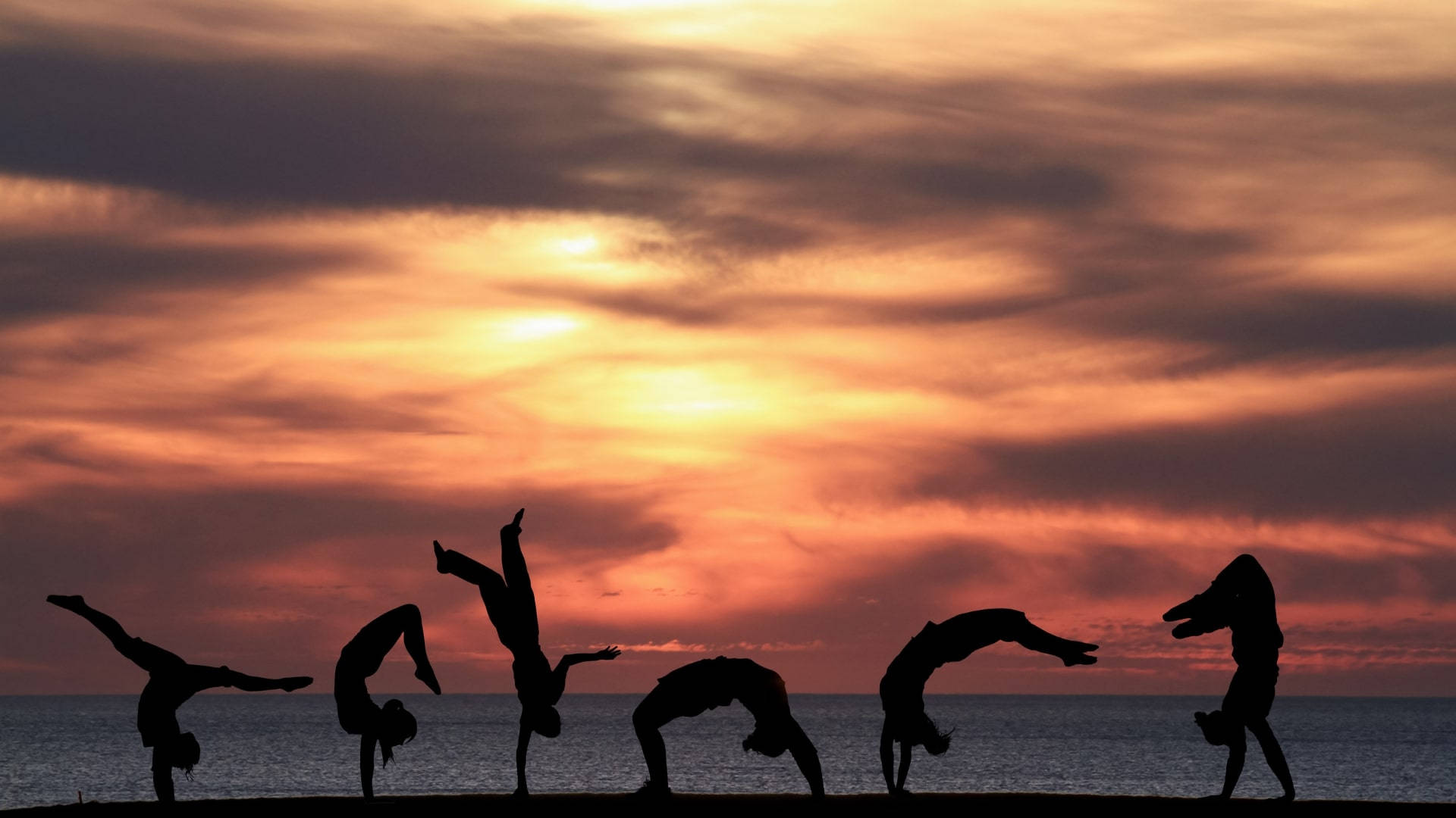Strandsolnedgang med tumlende silhuetter Wallpapers