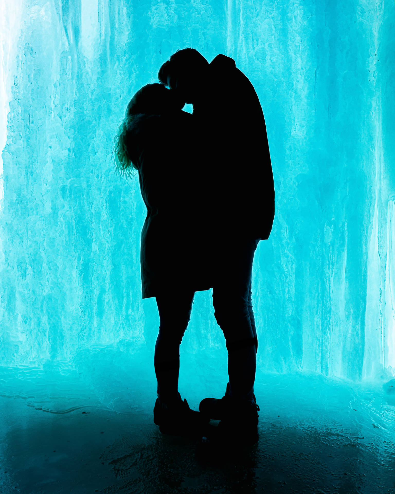 Kyssende par i kærlighedssilhuet mod blå isbaggrund. Kyssende elskende på Valentinsdag. — Kærlighed Wallpapers