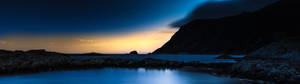 Ultrawide landskab med mørke bjerge og klart blåt vand. — 2560x1440 Wallpapers