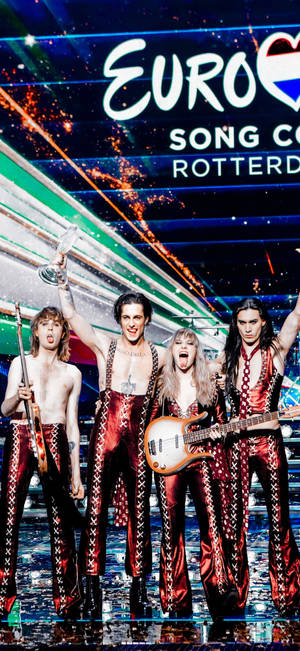 Maneskin stående på scenen baggrund — iPhone 16 Wallpapers