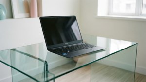 Et rent minimalistisk scene med en Chromebook på et glasbord.