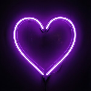 Et glødende neon lilla hjertesymbol.