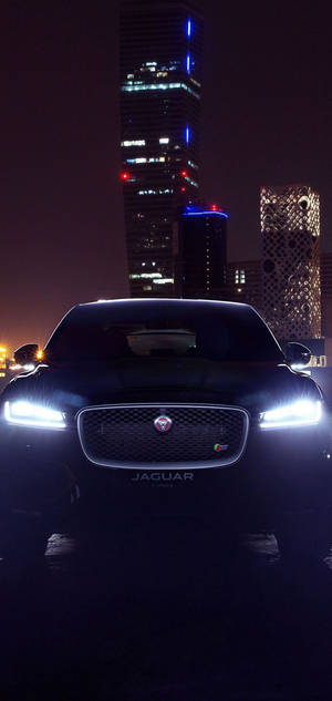Sort Jaguar-bil om natten med tændte forlygter tapet