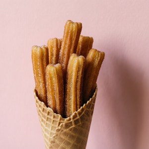 Stablede churros i en kegle mod en lyserød baggrund. — Pixel Watch 3 Wallpapers