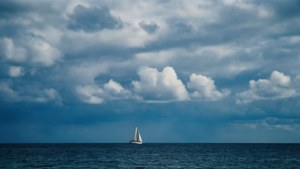 Tungt skydække over havet med en sejlbåd, fredfyldt maritimt tapet. — Himmeludsigt Wallpapers