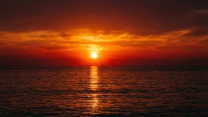 En symmetrisk solnedgang over havet med orange og røde spejlinger. — Himmeludsigt Wallpapers