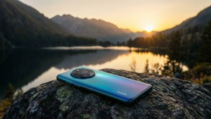 Huawei-telefon på en sten med udsigt over en bjergsø ved solnedgang, fredfyldt landskab. — Huawei Wallpapers