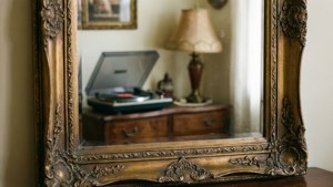 Et udsmykket vintage-spejl, der reflekterer et hyggeligt retro-interiør.